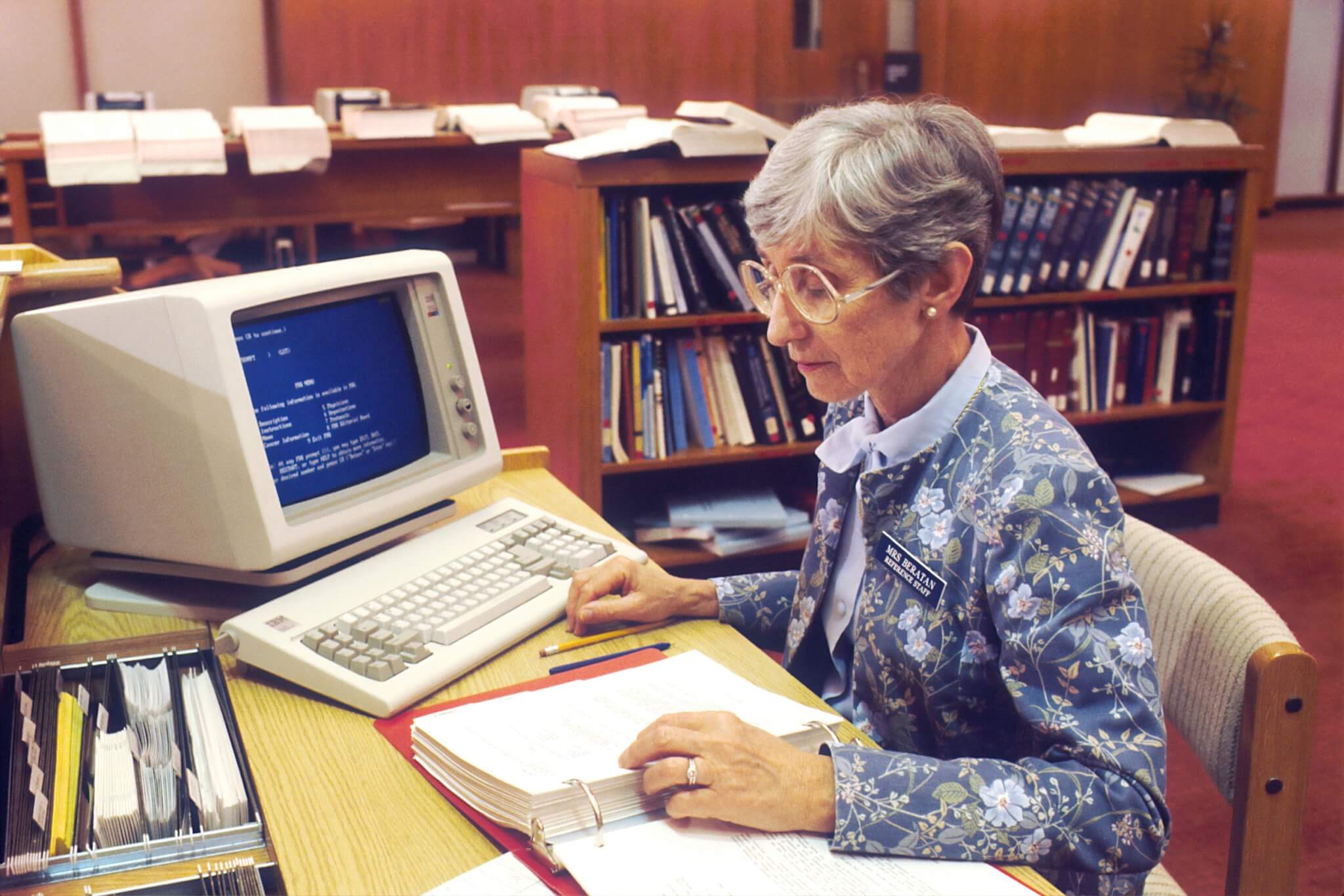 Elderly lady on retro computer in library studying